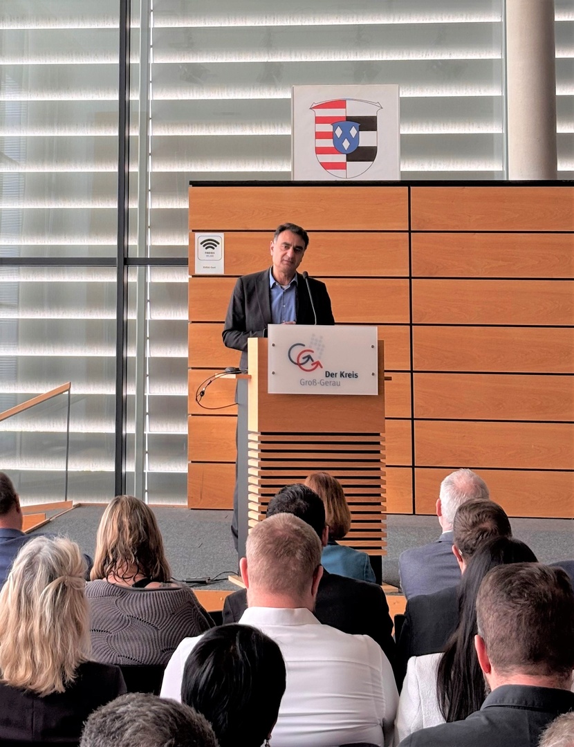 Adil Oyan begrüßte die Teilnehmenden des Arbeitsmarktpolitischen Impulses und steht an einem Rednerpult