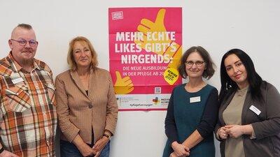 vier Personen vor einem Plakat