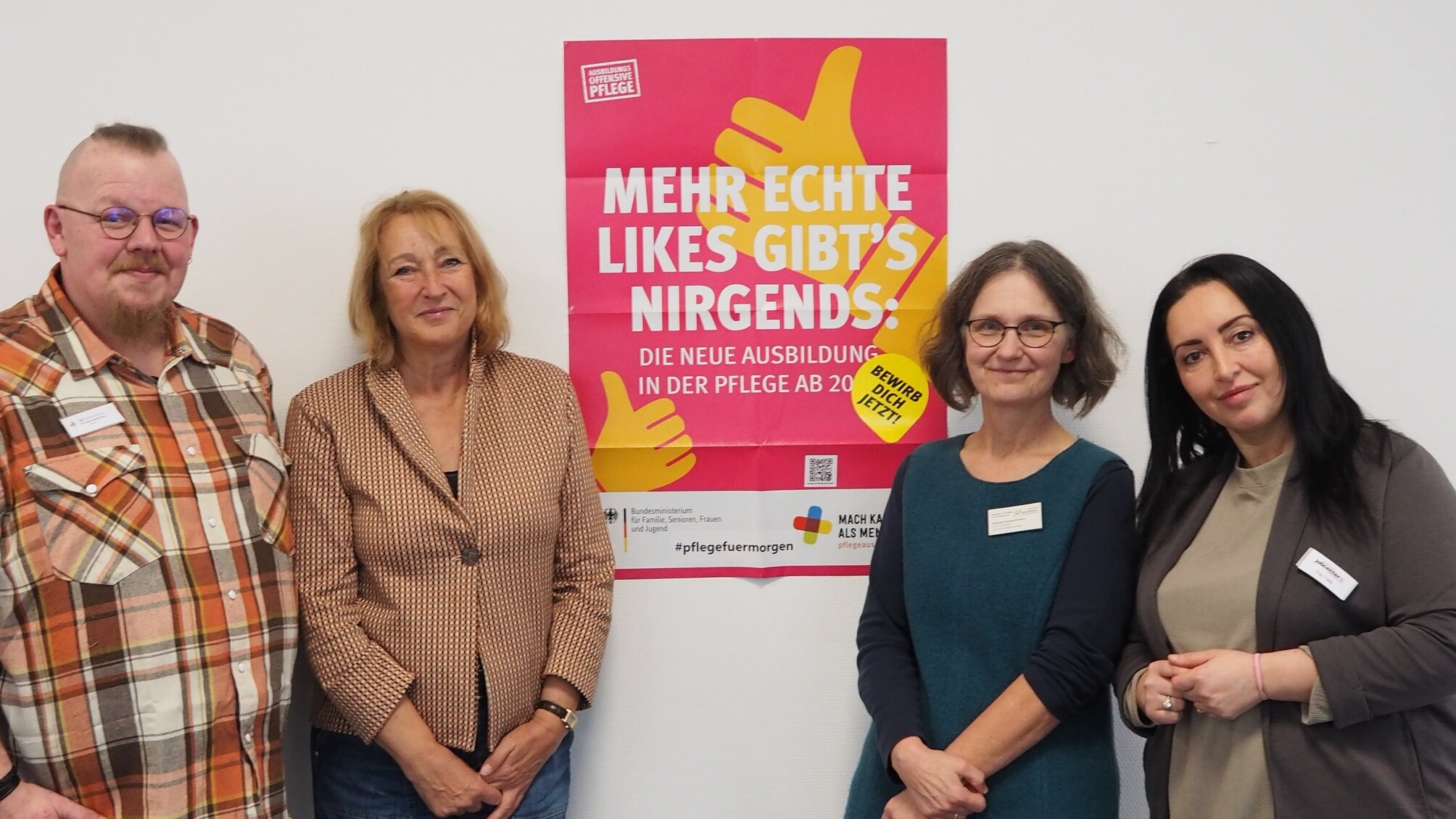 vier Personen vor einem Plakat