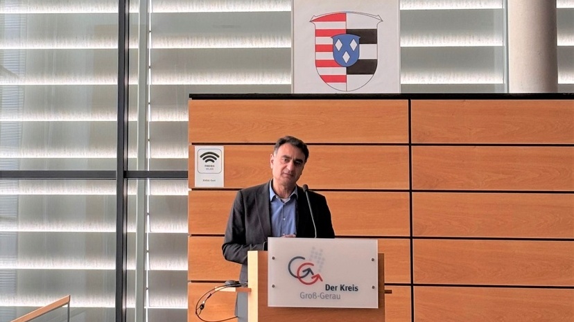 Adil Oyan begrüßte die Teilnehmenden des Arbeitsmarktpolitischen Impulses und steht an einem Rednerpult